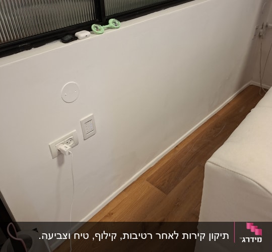קיר פנים צבוע בלבן בחלל מרוהט עם רצפת פרקט